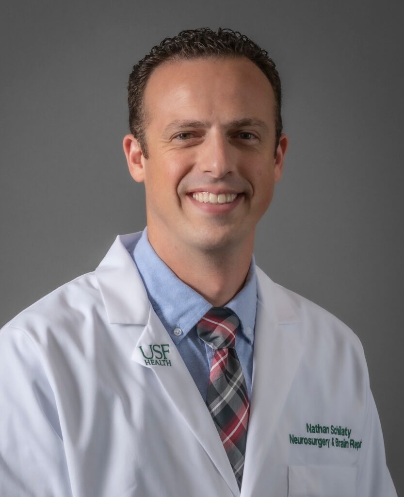Dr. Nathan Schilaty smiling with USF Health coat